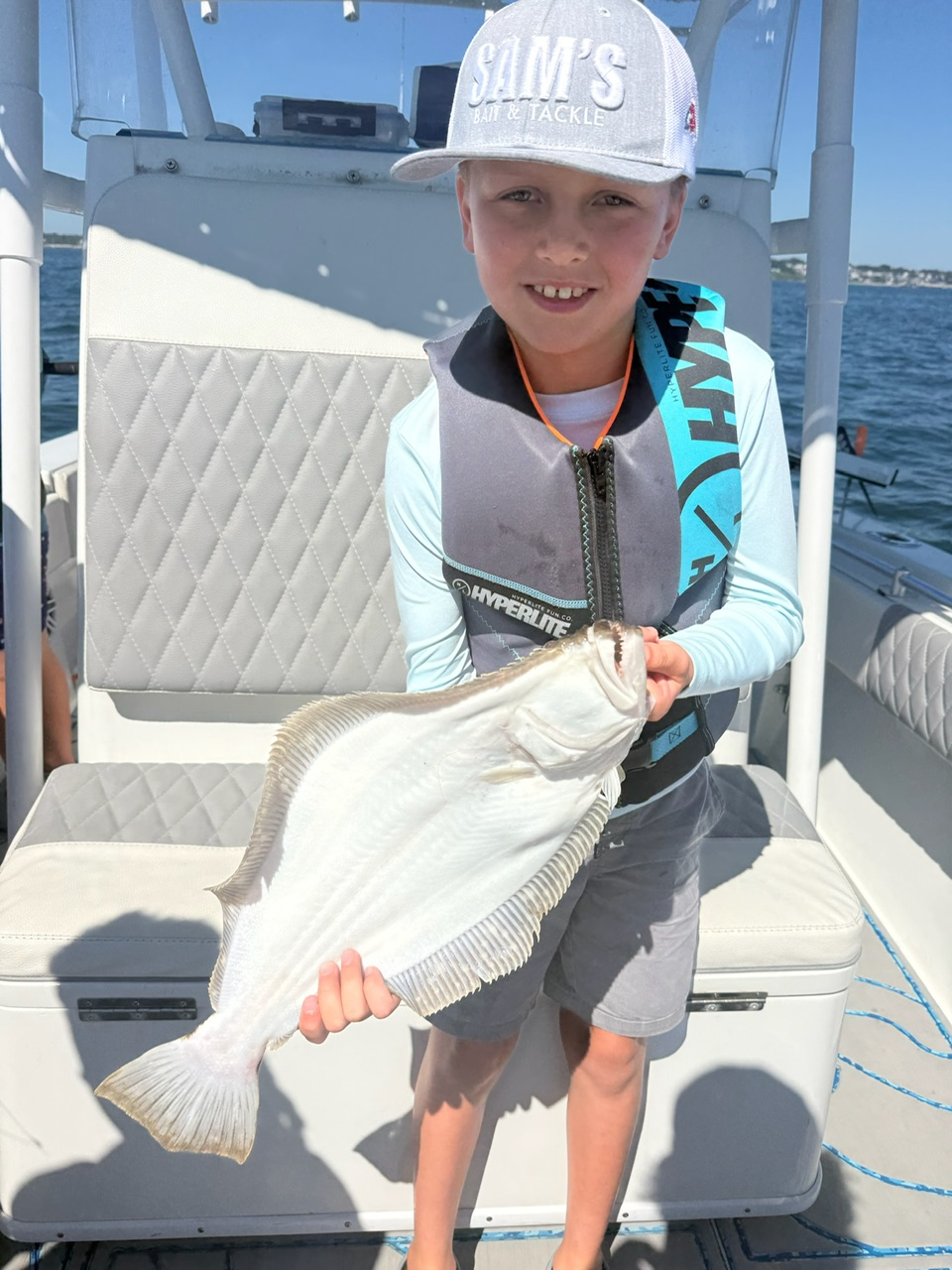 Young camper holding up a keeper fluke aboard the 28-foot Contender
