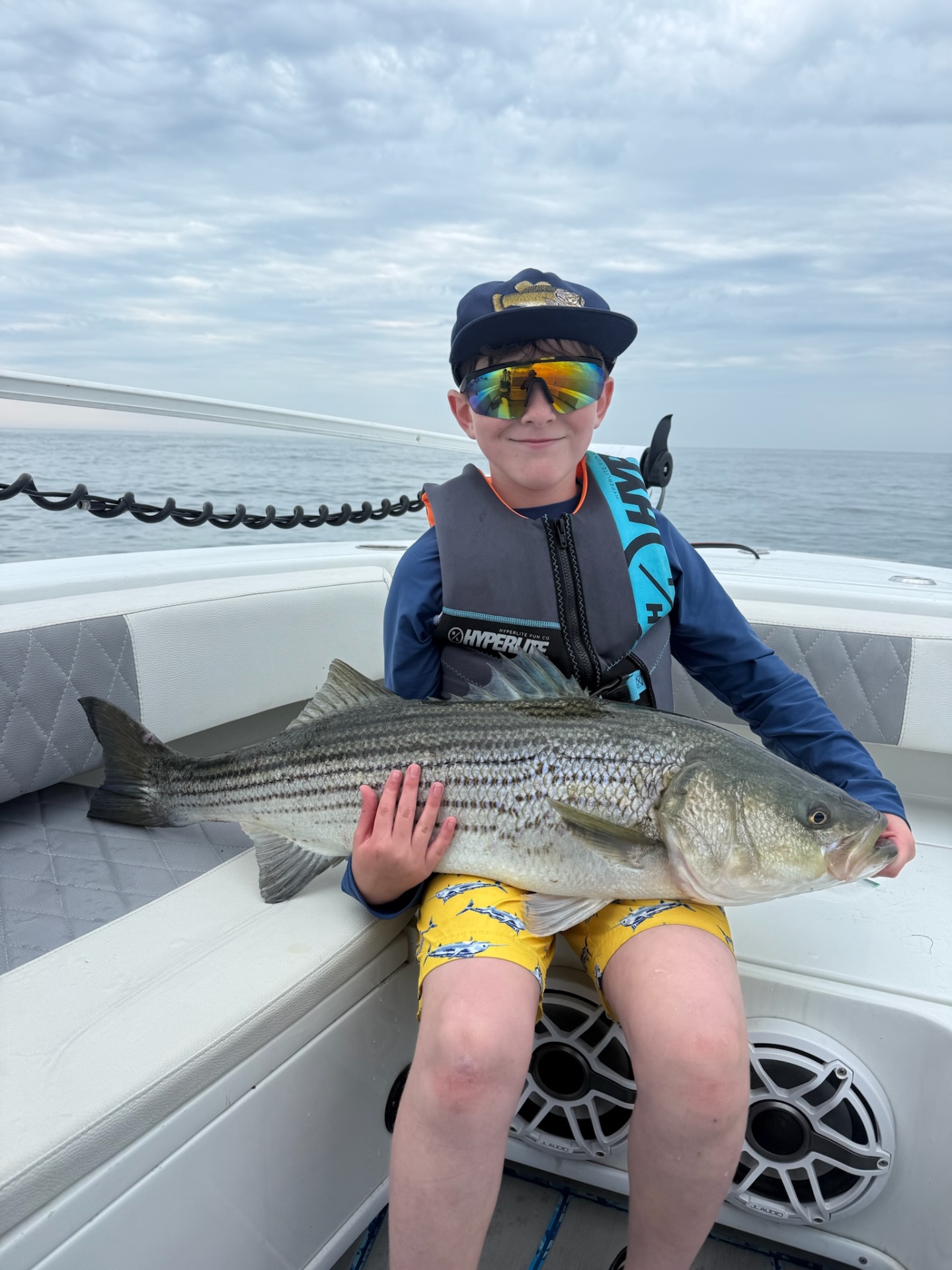 Academy camper in captain's hat with a big striped bass