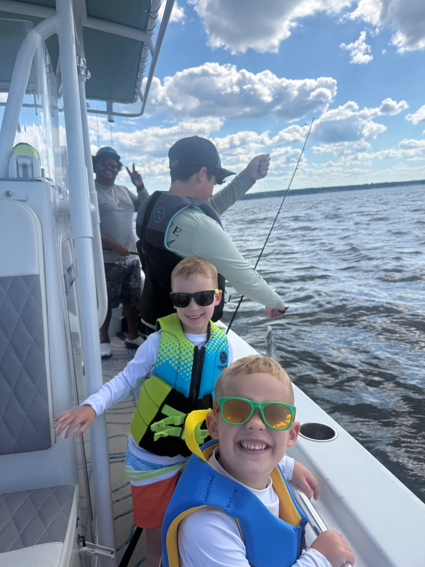 Buddies smiling in life vests on a family fishing trip
