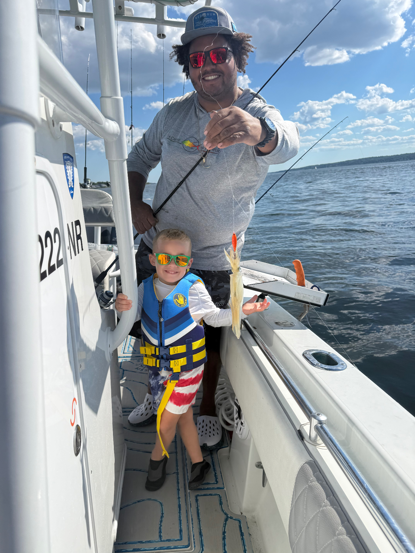 Young angler with Captain Justen holding up squid bait