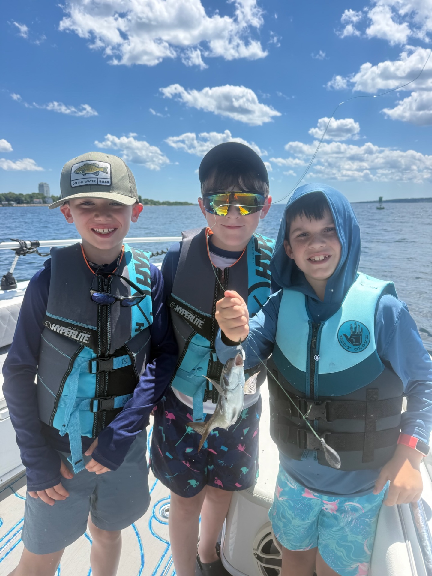 Three academy campers smiling with a fish on the bay