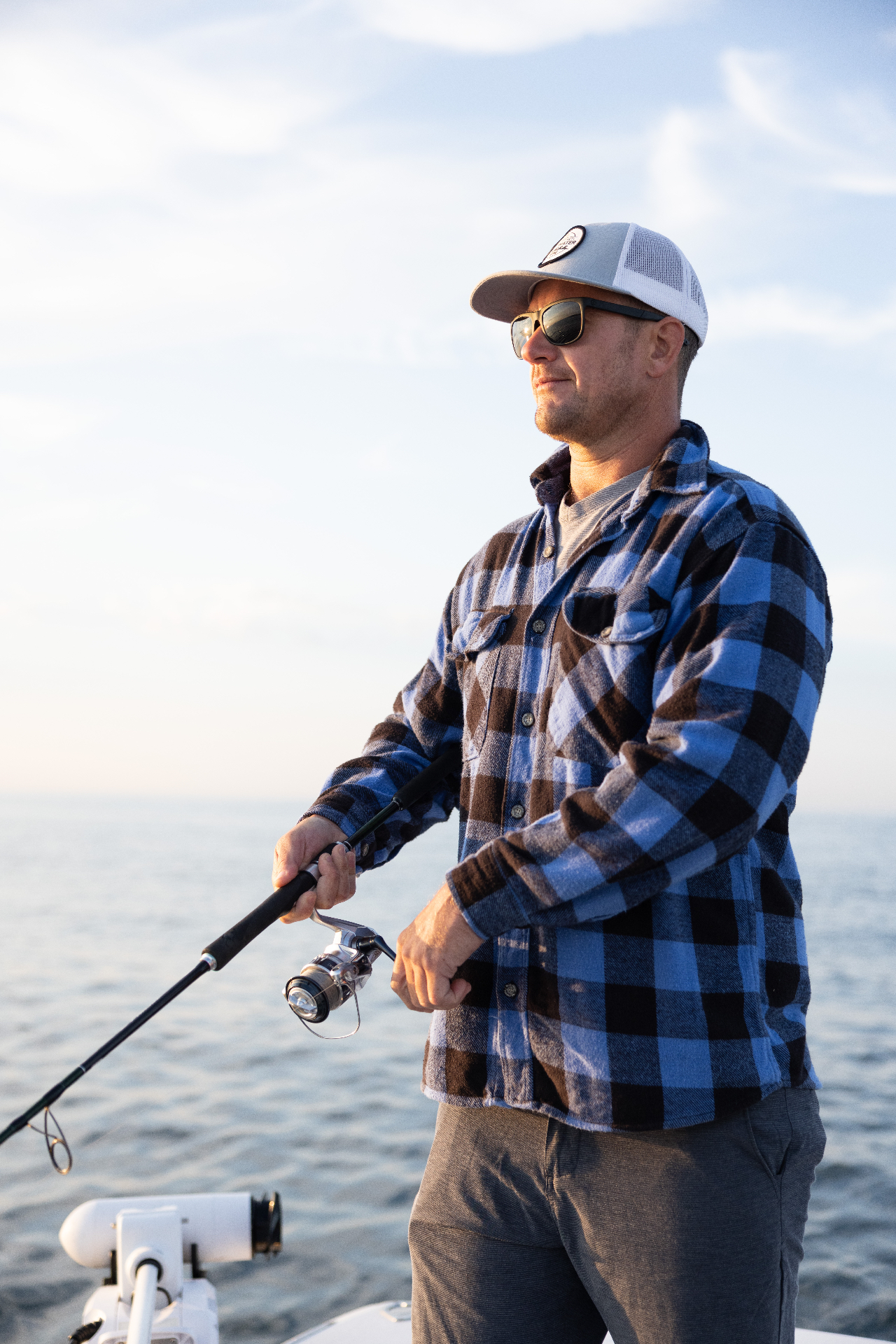 Angler in a flannel working a spinning rod at golden hour