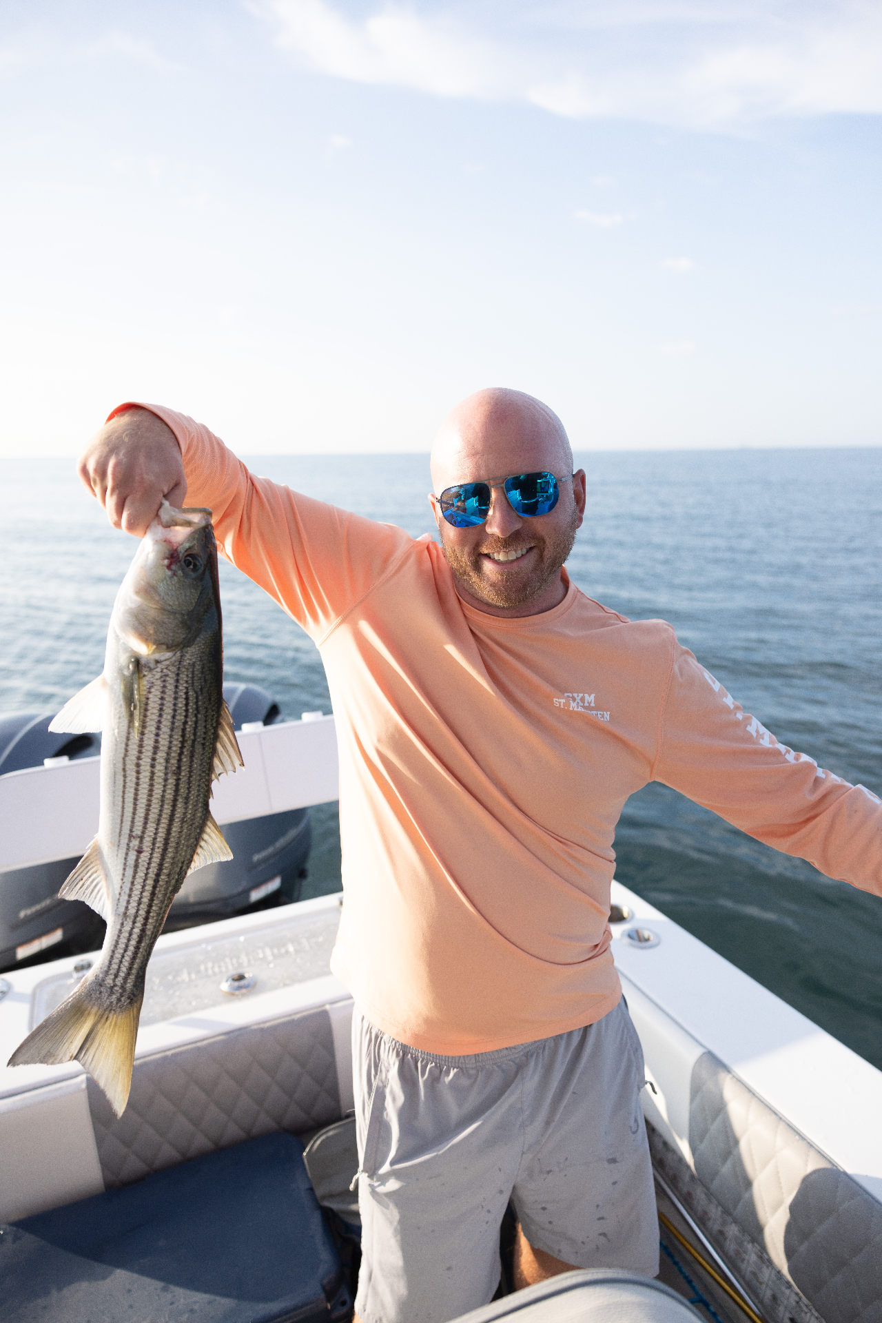 Angler holding up a striped bass on the bay